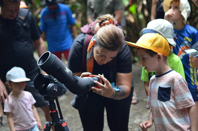 Guide francophone montrant la faune à des enfants avec une longue-vue à Manuel Antonio